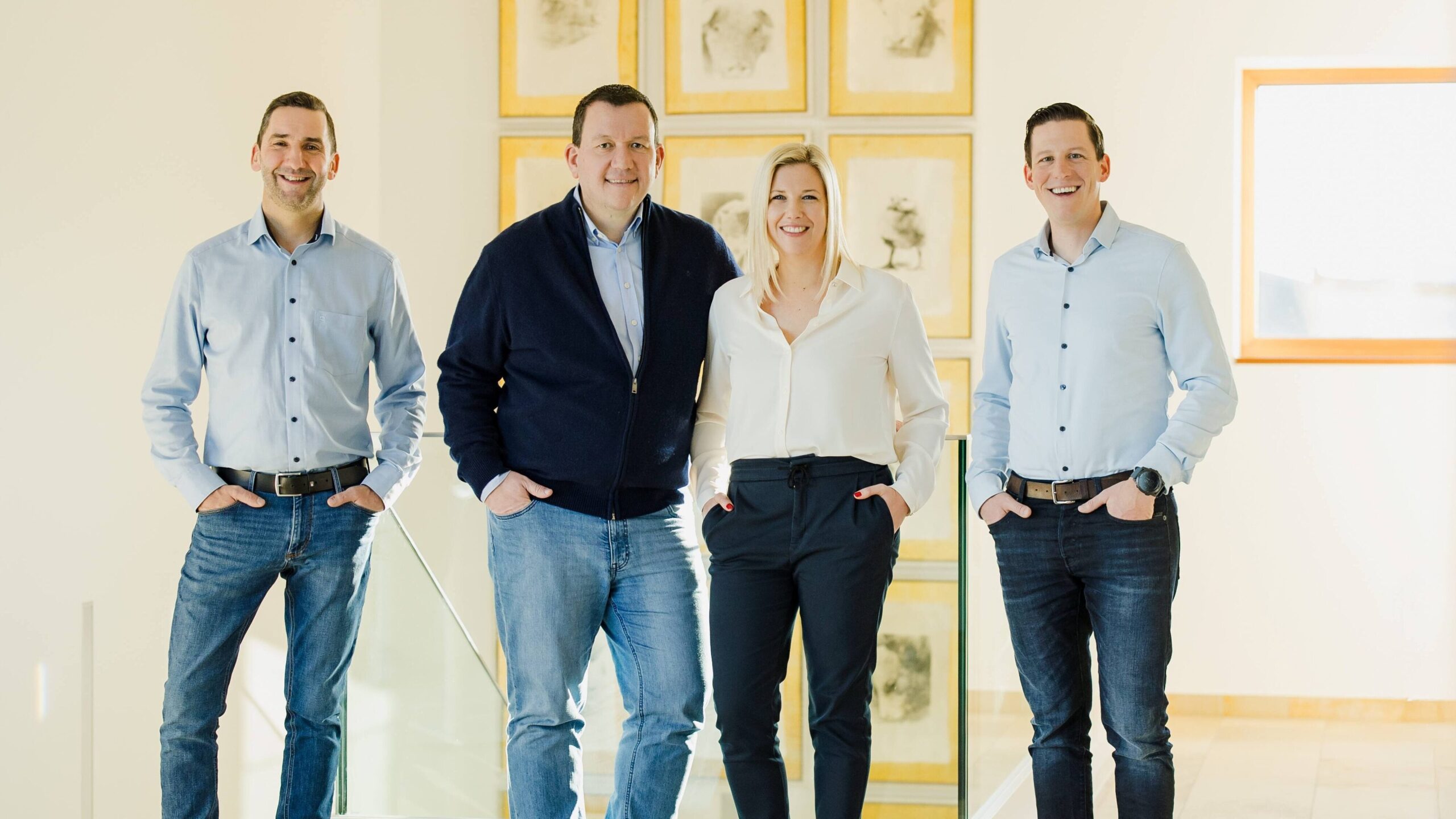 Vier Personen des Führungsteams posieren in einem hellen Raum